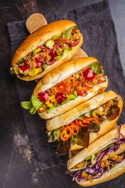 istock Hot dogs with assorted toppings on a dark background, top view. 1069485006