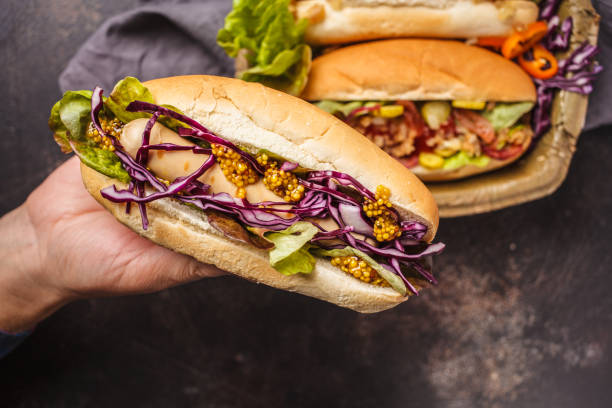 Hot dogs with assorted toppings on a dark background, top view.