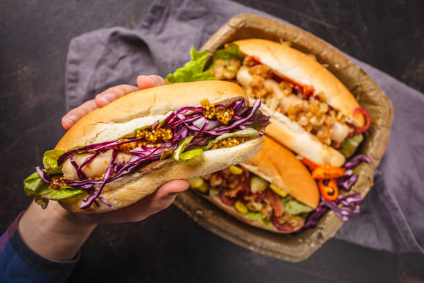 Hot dogs with assorted toppings on a dark background, top view.