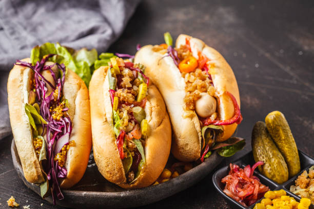 istock Hot dogs with assorted toppings on a dark background, top view. 1069485410
