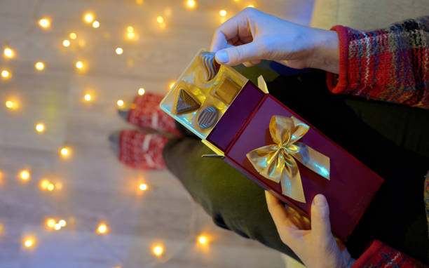 istock Woman Holding Chocolate Present Next To Christmas Lights 1069486164
