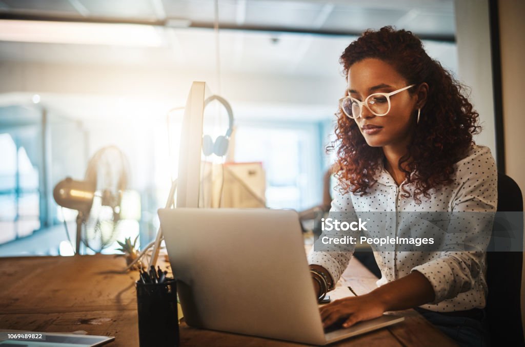 She gets it done whatever the hour Shot of a young businesswoman using a laptop during a late night at work Women Stock Photo