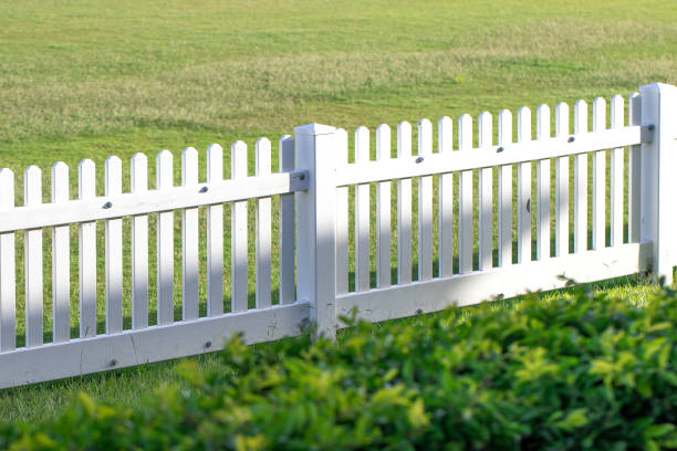 istock White picket fence in green grassy field on a sunny day 1069492850