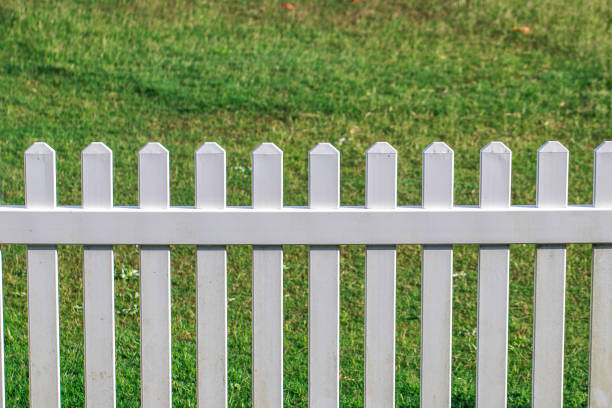istock White picket fence in green grassy field on a sunny day 1069492856