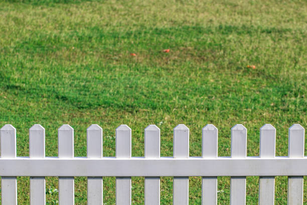 istock White picket fence in green grassy field on a sunny day 1069492866