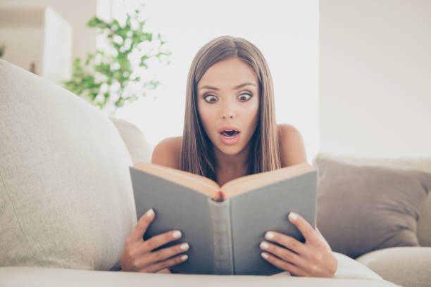 istock Unbelievable incredible unexpected plot cool book concept. Close up photo portrait of nice glad shocked lady holding hard cover of book in hand lying sitting on soft divan in light room indoor 1069495344