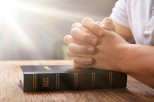 Sunlight Falling On Hand Over Bible While Praying