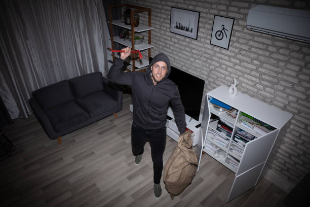 istock Thief With Crowbar And Sack Standing In House 1069504094