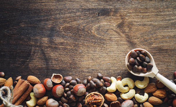 istock Different nuts on a wooden table. Cedar, cashew, hazelnut, walnuts and a spoon on the table. Many nuts are inshell and chistchenyh on a wooden background. 1069507872