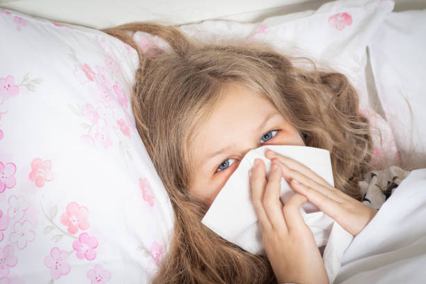 istock Girl in bed blowing nose 1069512380