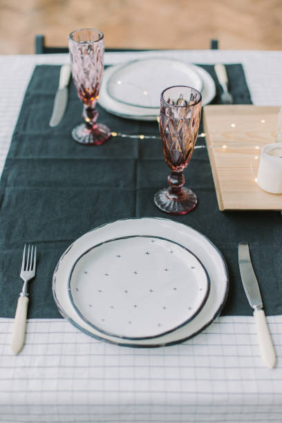 istock Table setting with black napkins, dotted plates, pink glasses and sparkling lights 1069514258