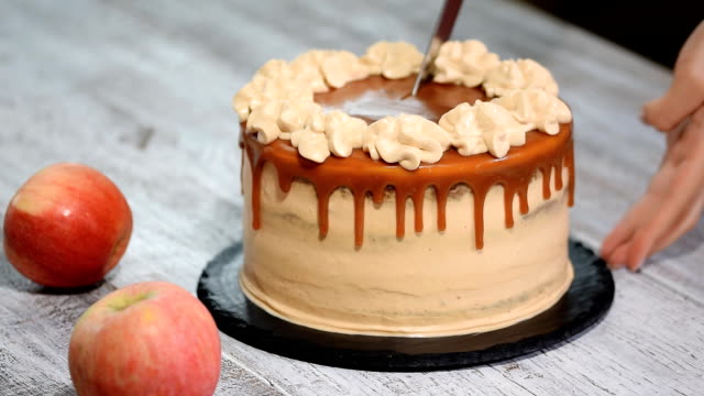 Cutting apple cake with spices, cinnamon, dried apples, creamy caramel in autumn style.