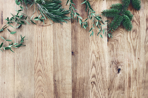 Christmas background. Border, frame of green fir, eucalyptus and pine tree branches on old wooden oak table. Winter festive banner. Vintage look, flat lay, top view.
