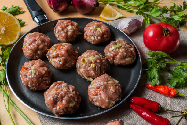 istock Homemade raw beef meatballs on a pan, before cooking, with vegetables. 1069516318