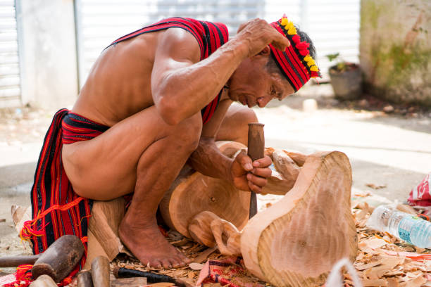 Banaue, Philippines - April 28, 2017: Banaue  view showing Ifugao man doing a wood carving using chisel and wearing traditional clothes