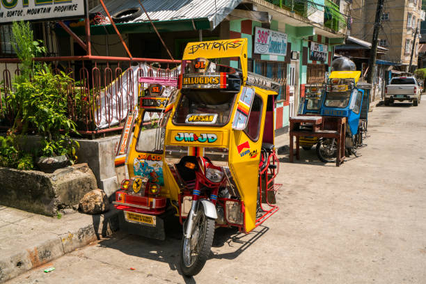 Tricycles and Car parked on the street in Banaue, Philippines Banaue, Philippines - April 29, 2017: Banaue  view showing tricycles and car parked on the street, houses and wires can be seen on the background philippines tricycle stock pictures, royalty-free photos & images