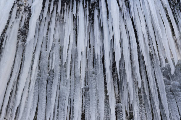 un sacco di ghiaccioli vicino alla cascata islandese skógafoss. - icicle hanging snow moving down foto e immagini stock