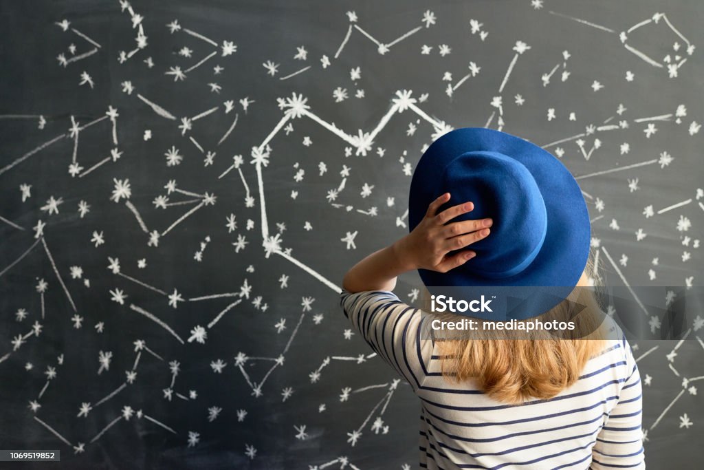 Constellation in the shape of a heart Rear view of young woman in striped shirt and hat looking at constellation in the shape of heart Astrology Stock Photo