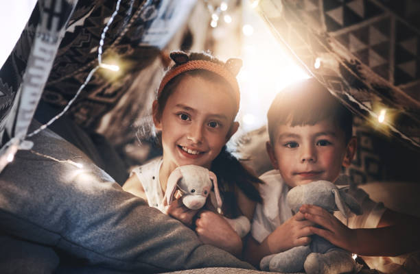 Happy boy and girl playing at home in a tent