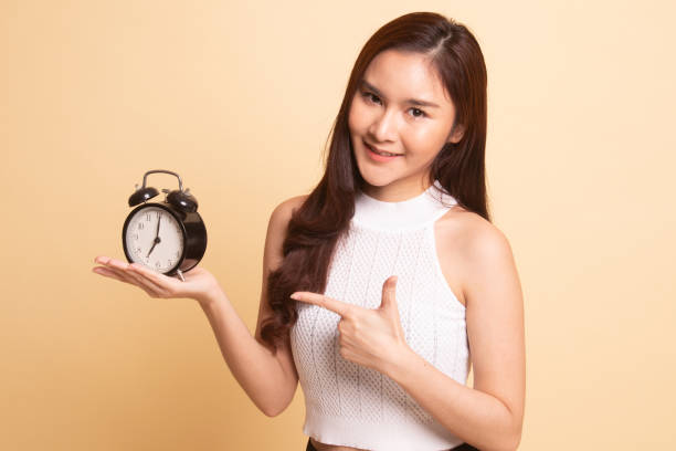 istock Young Asian woman point to a clock. 1069520816