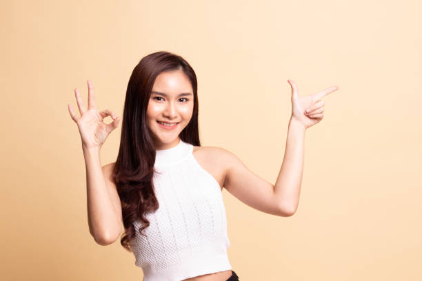 istock Young Asian woman point and show OK. 1069520880