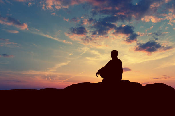 istock man meditating pastel on high mountain in sunset background. copy space 1069521210