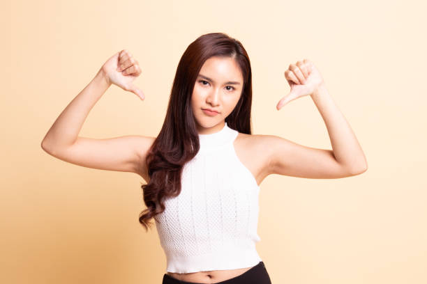 istock Unhappy Asian girl show thumbs down with both hands. 1069521326