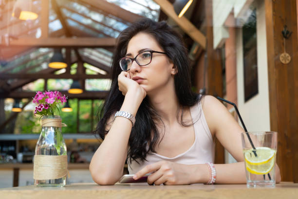 istock Sad girl with phone in cafeteria 1069528806
