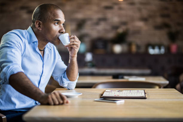 istock Black pensive businessman drinking coffee in a cafe. 1069531528