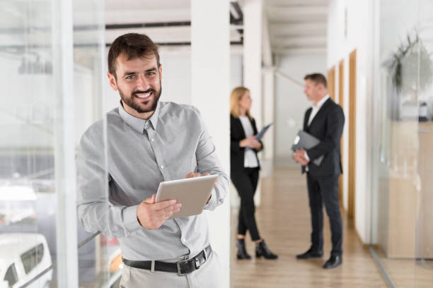 istock Smiling cheerful young man in office hall with digital tablet 1069532326