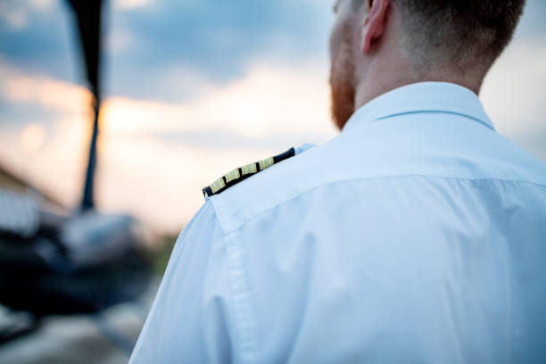Rear view of helicopter pilot standing in front of helicopter