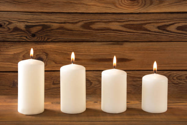 Four white candles against wooden background