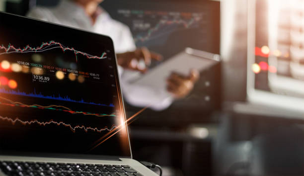 istock Laptop and data stock market on screen. Businessman using tablet and analyzing stock exchange online in monitoring room background, forex trading graph, stock market and financial investment concept. All on laptop screen are design up. 1069541600