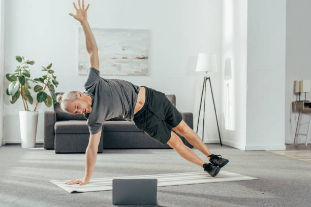 istock athletic man in sportswear practicing side plank and looking at laptop 1069543710