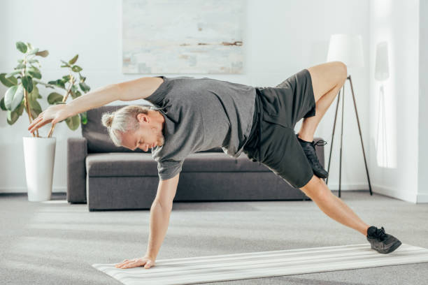 istock flexible athletic man in sportswear practicing side plank on yoga mat at home 1069543730