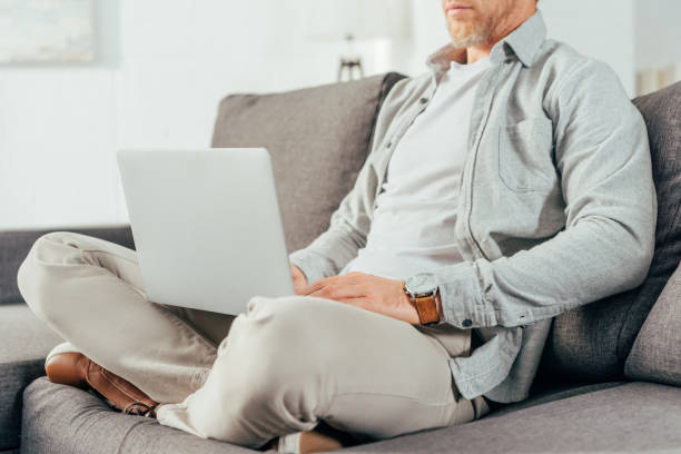 istock cropped shot of man sitting on couch and using laptop 1069544678