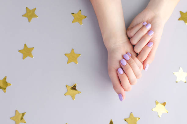 istock Hands with purple manicure on a gray background with asterisks. 1069548066