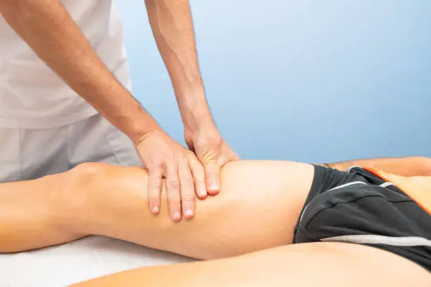 Quadriceps massage to an athlete by a physiotherapist.