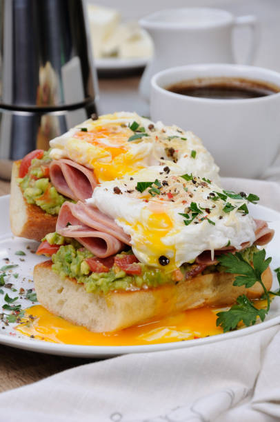 istock poached  eggs with avocado, tomatoes, slices of ham on a baguette for breakfast 1069560102