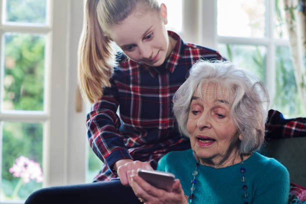 adolescentes mostrando la nieta abuela como uso del teléfono móvil - grandmother granddaughter senior adult teenager fotografías e imágenes de stock