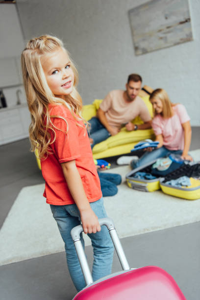 istock kid holding suitcase while family packing for summer vacation on background, travel concept 1069563120