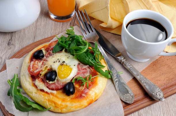 istock Mini pizza with sausage and egg and arugula, a cup of coffee for breakfast 1069565844
