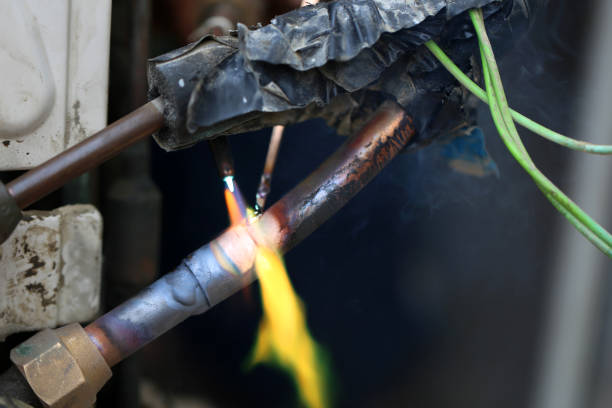 istock Technician are soldering a coil with copper in order to fix leakage of air compressor. This is a oil and piping problem of air-conditioner unit. 1069566202
