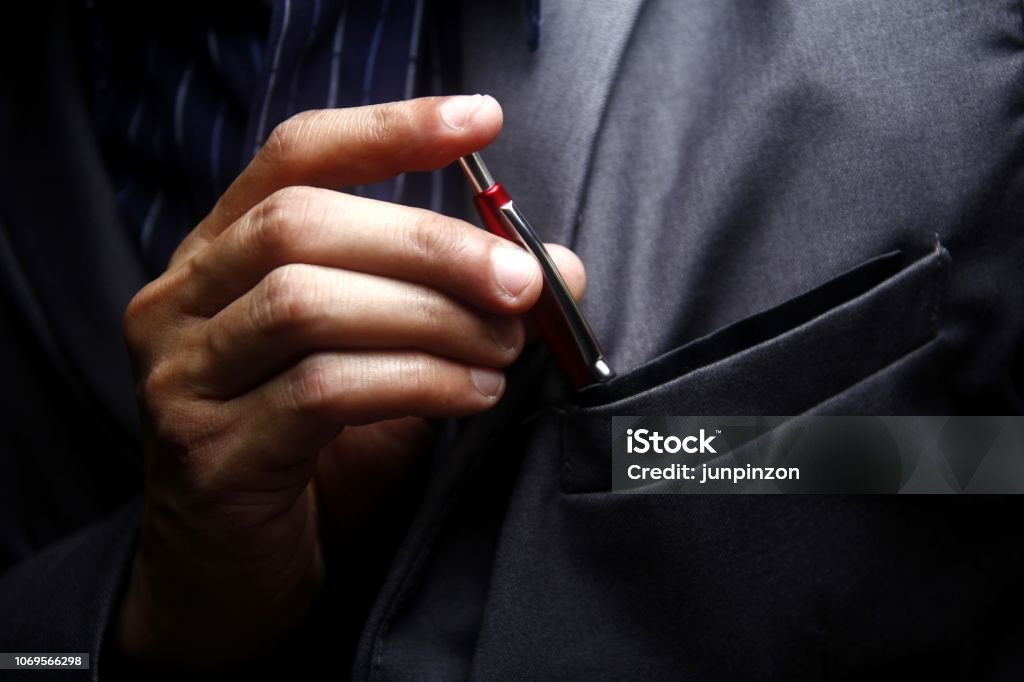 Man inserting a pen to his suit's pocket Photo of a man inserting a pen to his suit's pocket Pen Stock Photo