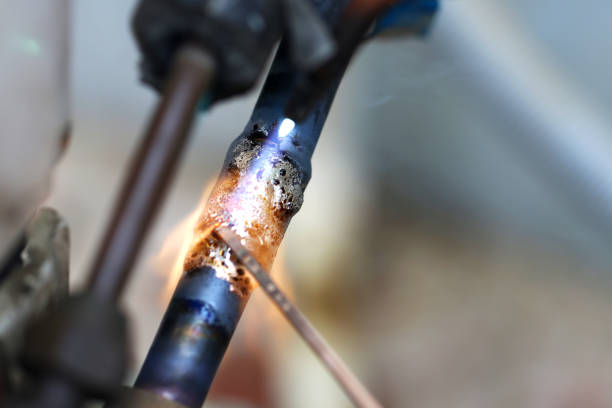 Technician are soldering a coil with copper in order to fix leakage of air compressor. This is a oil and piping problem of air-conditioner unit.