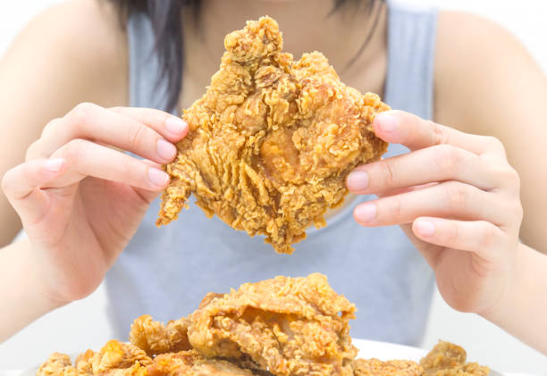 istock Woman holding and eatting fried chicken in white plate on white table 1069578080