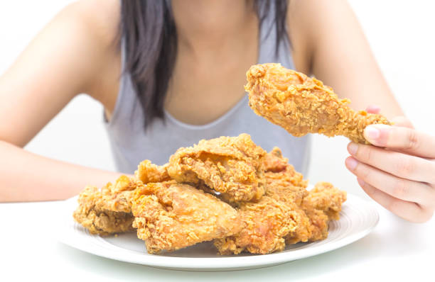 istock Woman holding and eatting fried chicken in white plate on white table 1069578130