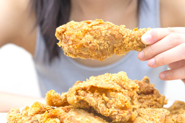 istock Woman holding and eatting fried chicken in white plate on white table 1069578200