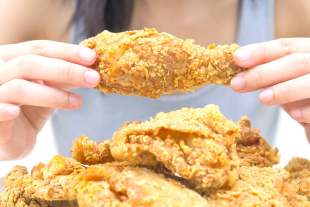 istock Woman holding and eatting fried chicken in white plate on white table 1069578308