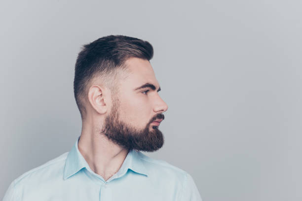 istock Close up half turned studio photo portrait of handsome focused with modern trendy hipster haircut boss looking away aside wearing light blue formalwear clothing isolated on gray background copy space 1069578476